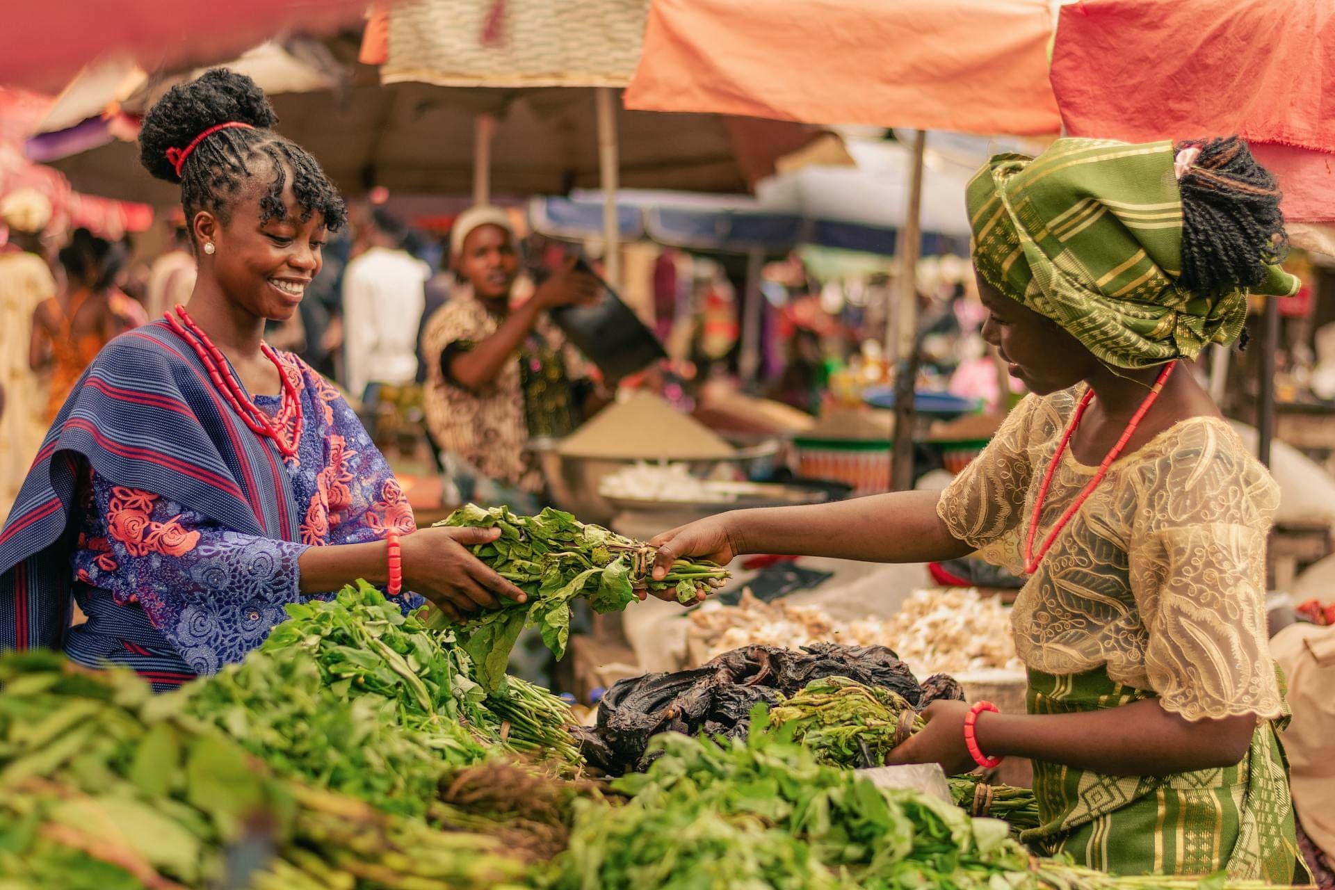 Two women trading fresh greens at a market