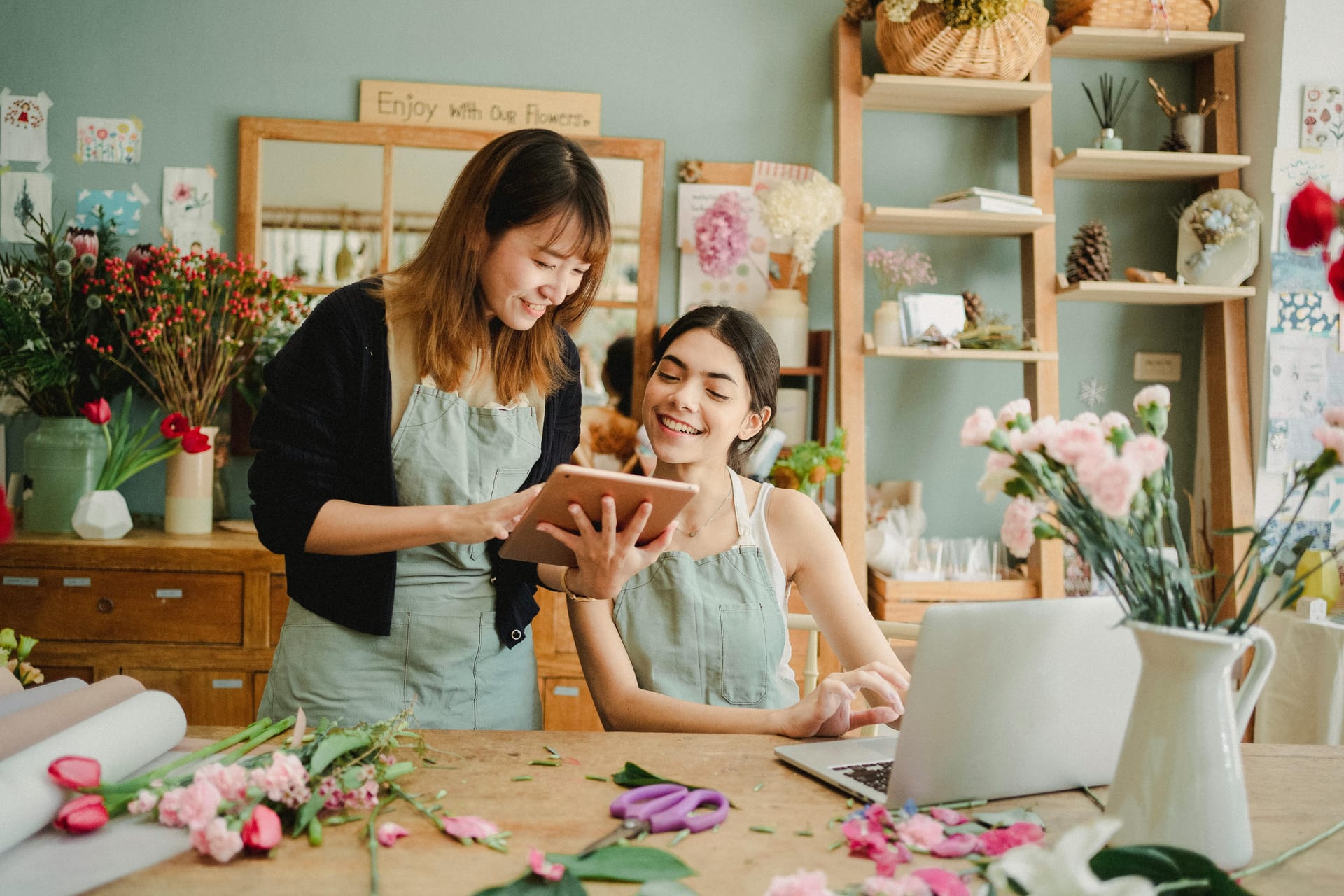 Two female florists arranging flower bouquets in a cozy workshop, creating beautiful floral designs.